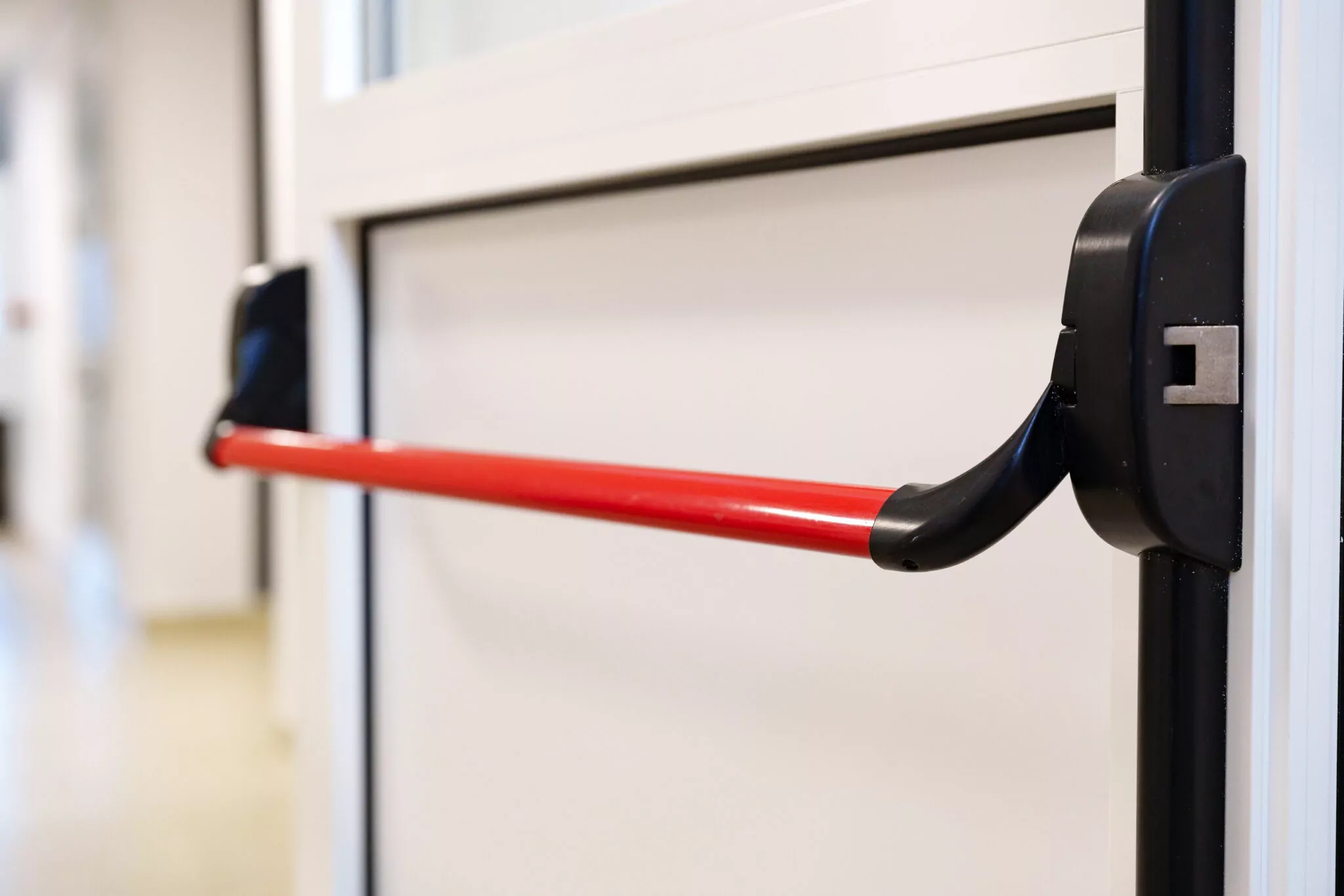 Door safety device with red handle installed in a modern commercial building corridor for improved accessibility